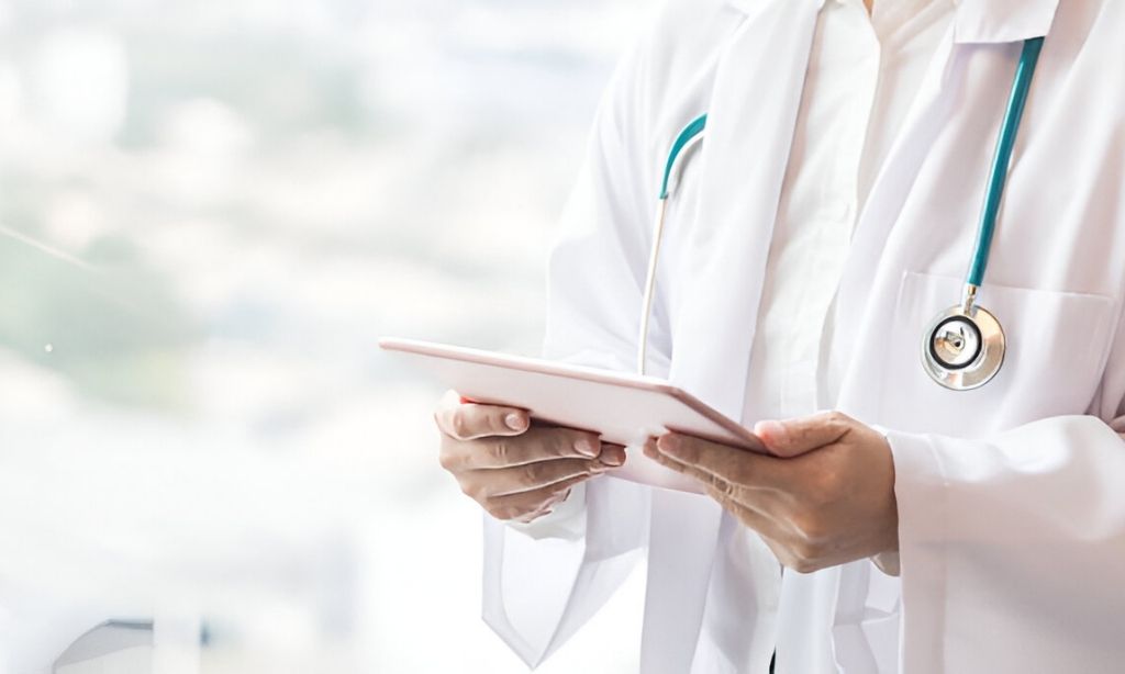 Doctor holding a tablet to access patient health records—highlighting the importance of strong online presence and digital engagement in modern healthcare practices